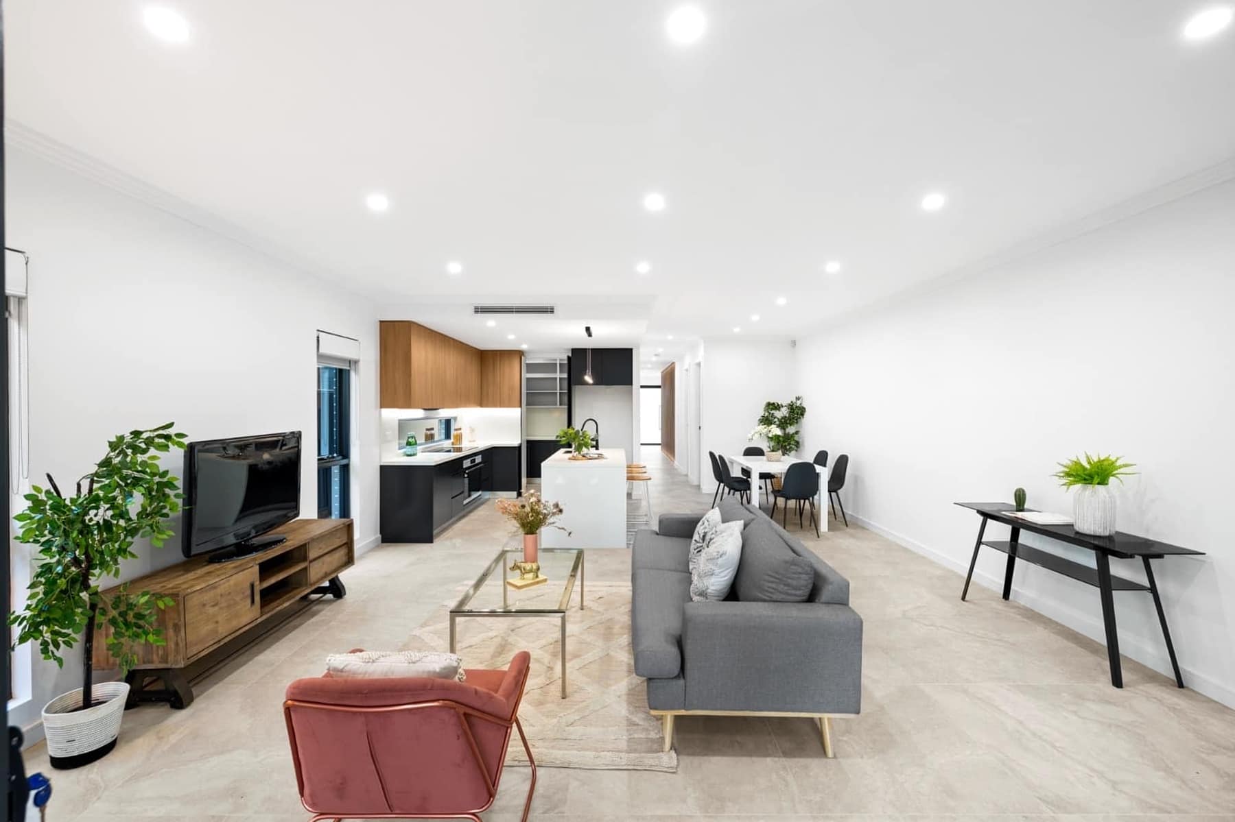 Open-plan living, dining and kitchen zone with stone island bench and black joinery