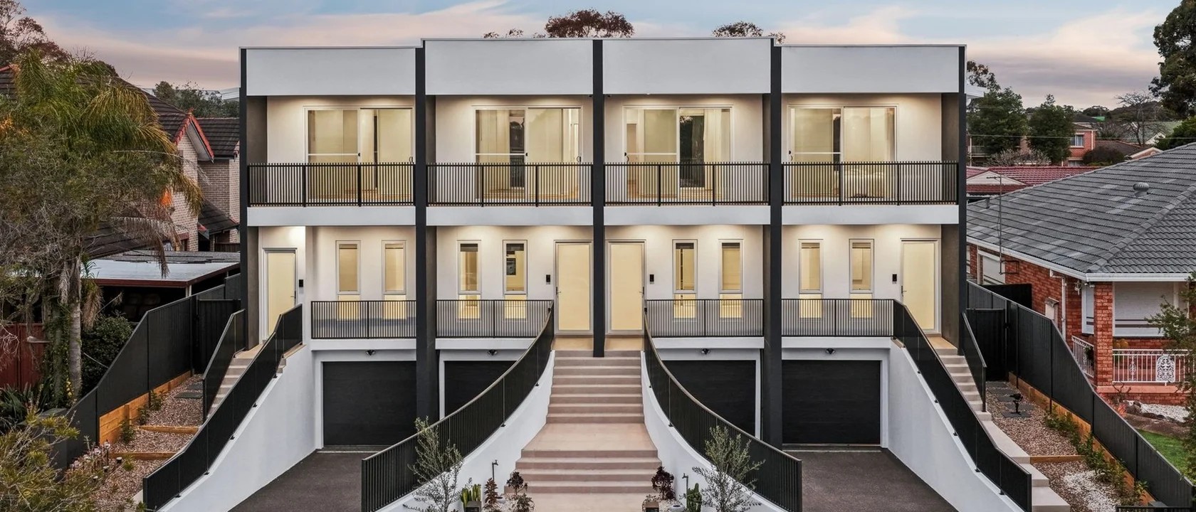 Twilight view of the four Carbine Close terraces in Casula, with ramped entries and twin balcony lines