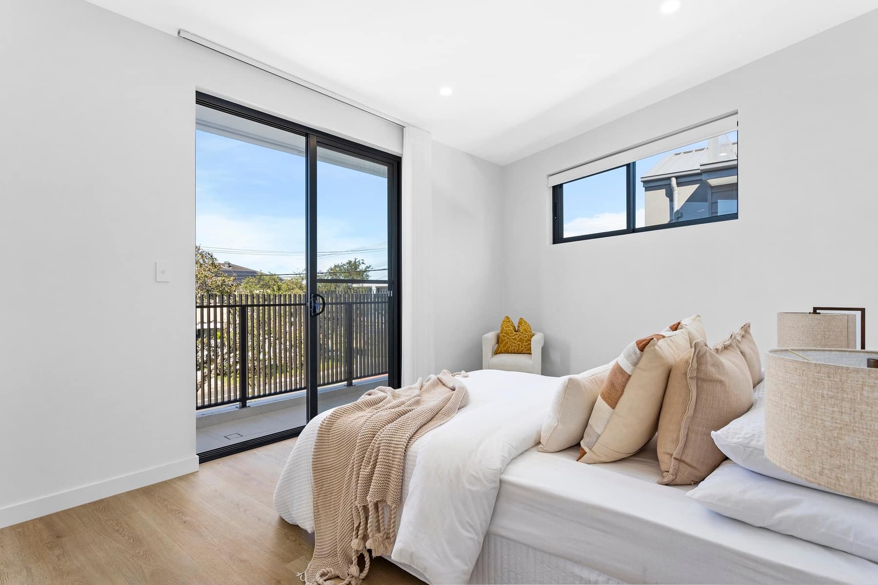 Bedroom with balcony access and light timber floors in a Stockton Avenue townhouse